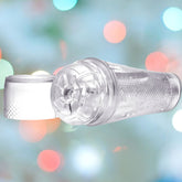 A transparent water filter with a white cap is set against a backdrop of blurred multicolored lights, reminiscent of the sleek design offered by the Fleshlight brand's Flight Aviator Masturbating Sleeve. Its cylindrical shape and perforated surface provide effective water filtration while allowing for customizable features to optimize performance.